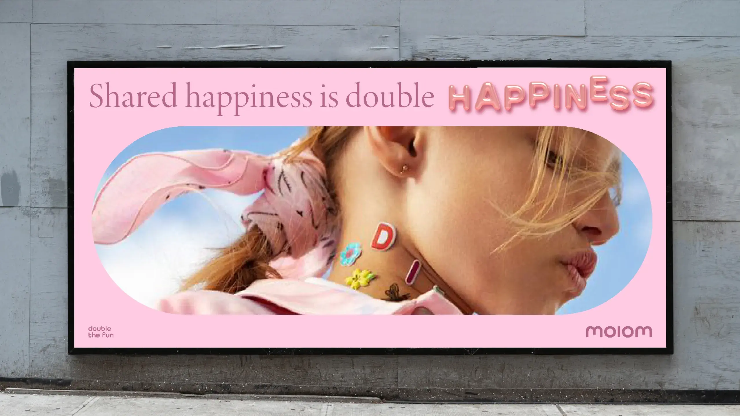 A woman with a pink scarf and colorful neck tattoos is featured on a pink billboard with the text "Shared happiness is double happiness."