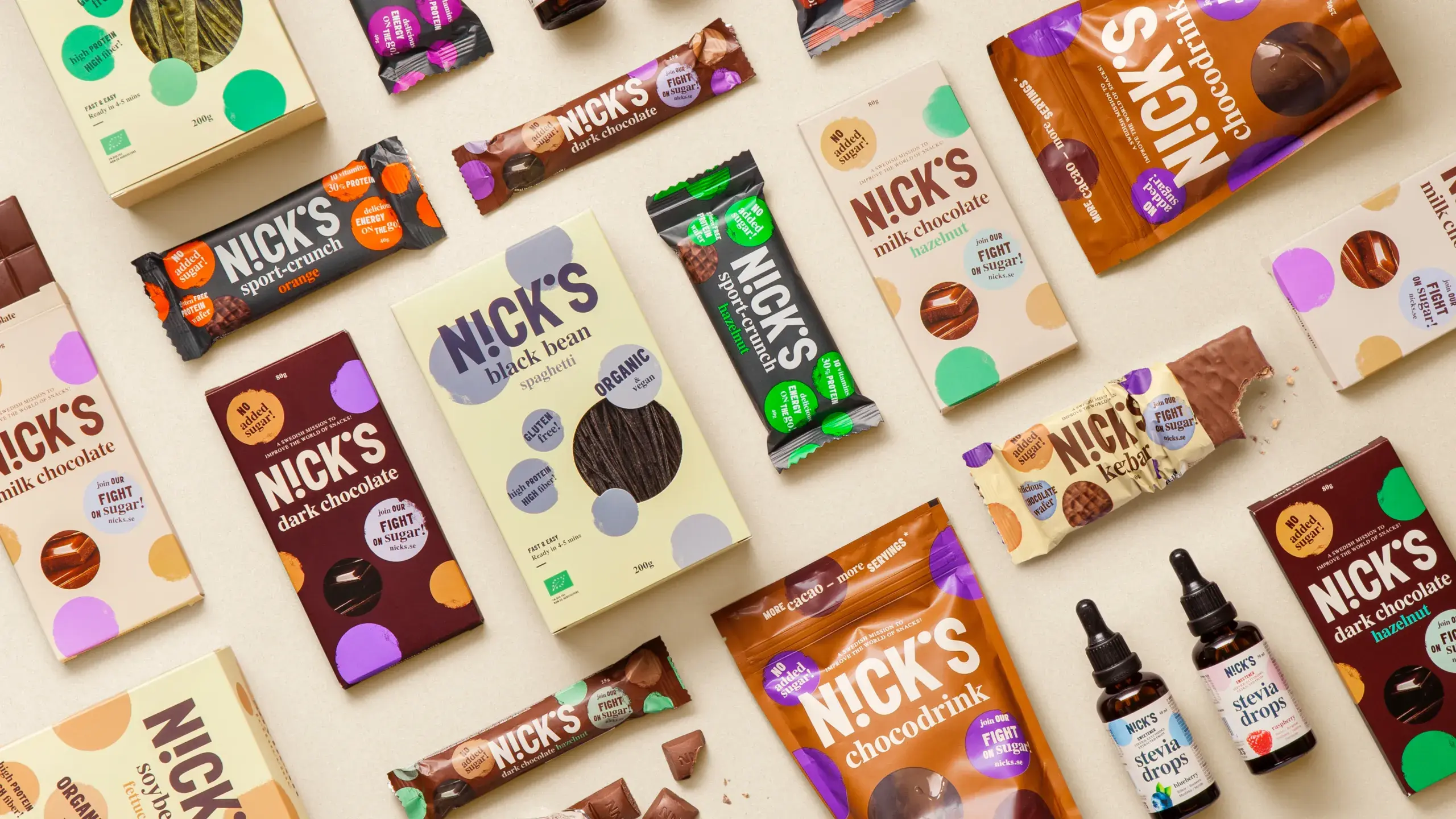 An assortment of NICK'S chocolate products, including bars, bags, and bottles, arranged on a beige background.